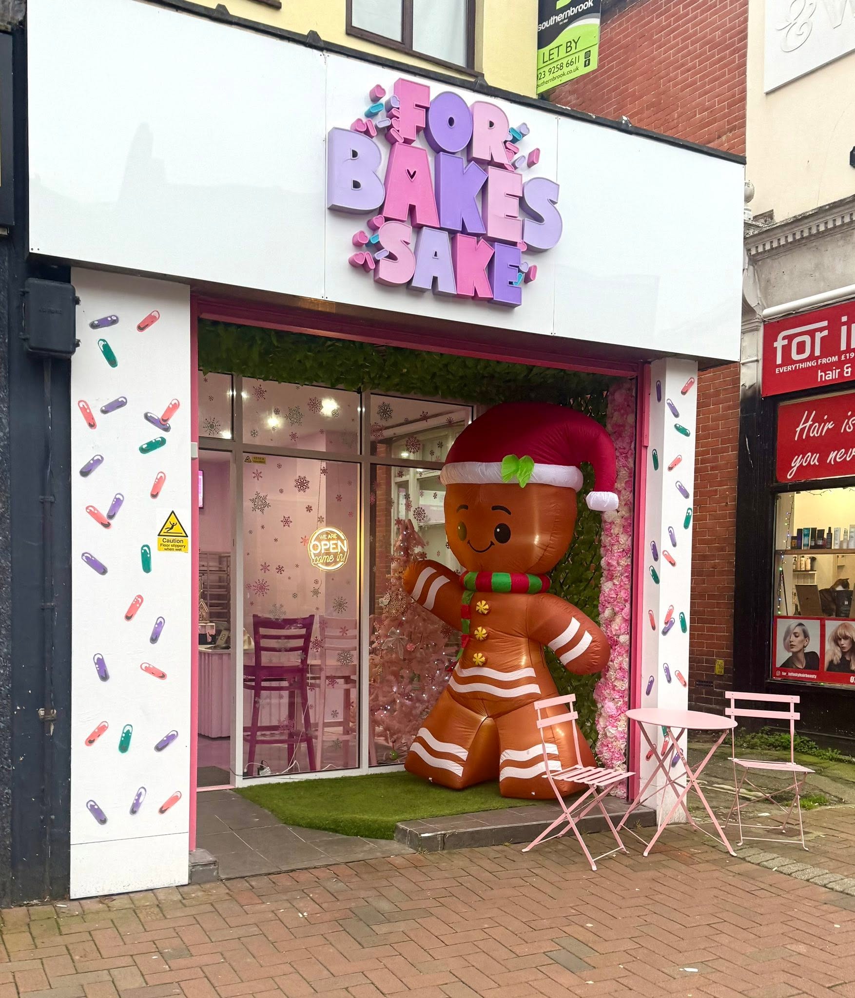 Our For Bakes Sake bakery, with its pink shop sign and festive window display.